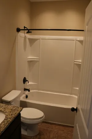 a bathroom with a granite countertop sink toilet and shower