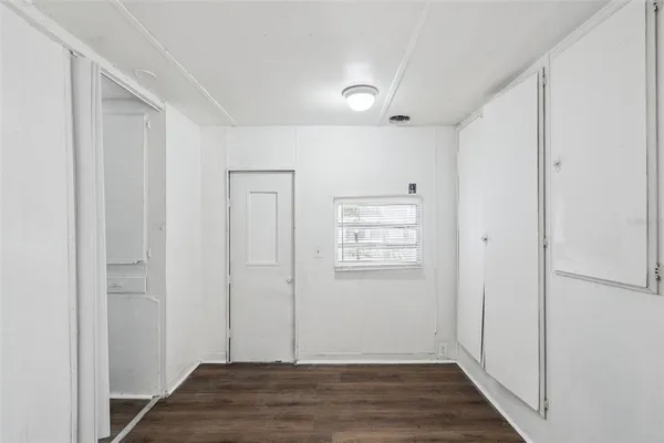 an empty room with wooden floor closet and windows