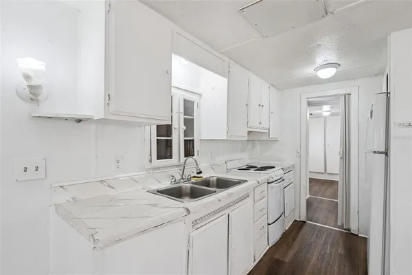 a kitchen with granite countertop white cabinets and white appliances