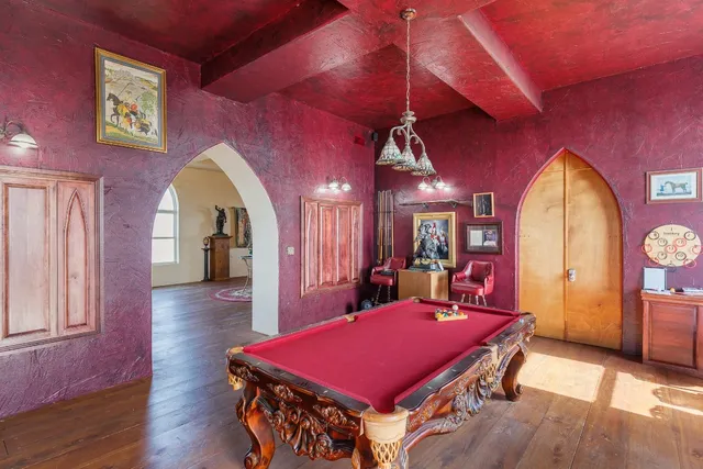 a room with furniture pool table wooden floor and windows