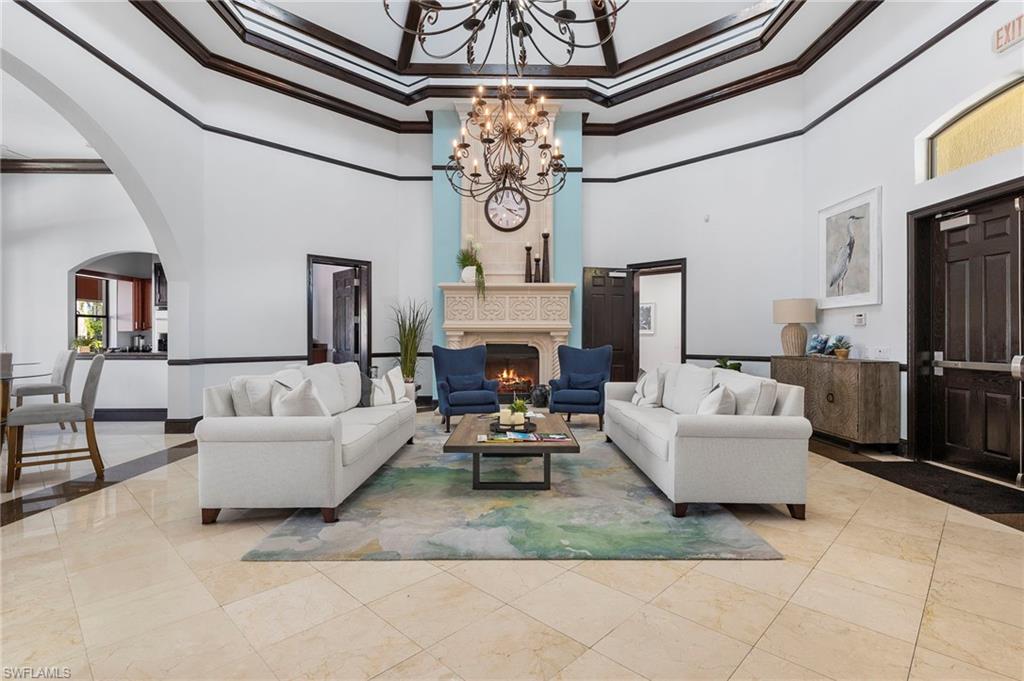 12940 Positano Circle, Unit 204 Naples, FL 34105 - Photo 32 of 39 a living room with fireplace furniture and a chandelier