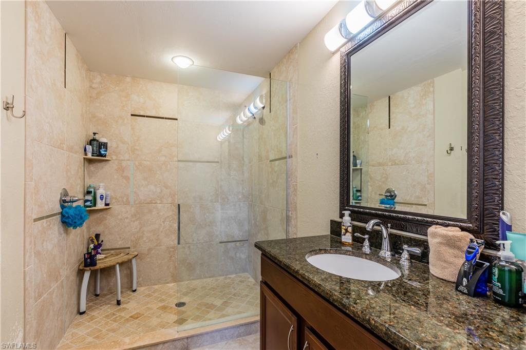 102 Cedar Crest Court Naples, FL 34113 - Photo 10 of 15 a bathroom with a granite countertop sink a mirror and a shower