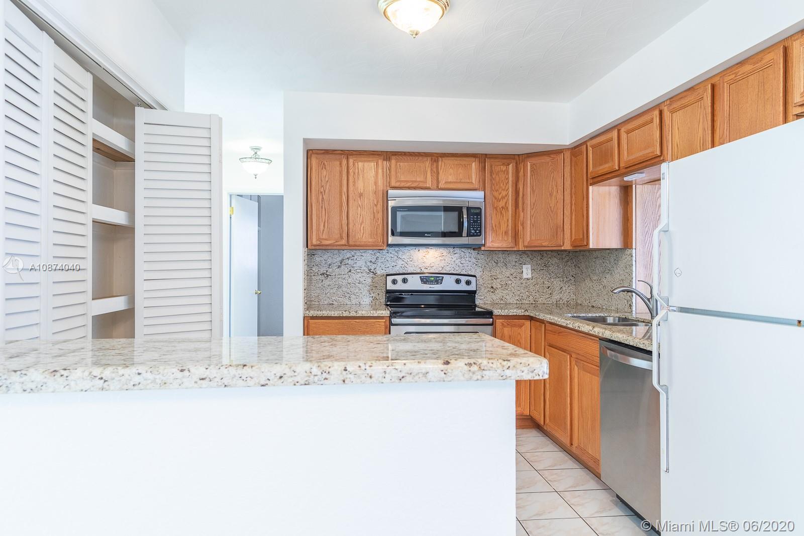 5416 Jefferson Street Hollywood, FL 33021 - Photo 28 of 70 a kitchen with stainless steel appliances granite countertop a stove a refrigerator a sink a oven with wooden cabinets