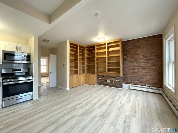 a view of an empty room with a window and wooden floor