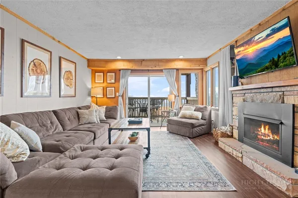 a living room with furniture a flat screen tv and a floor to ceiling window