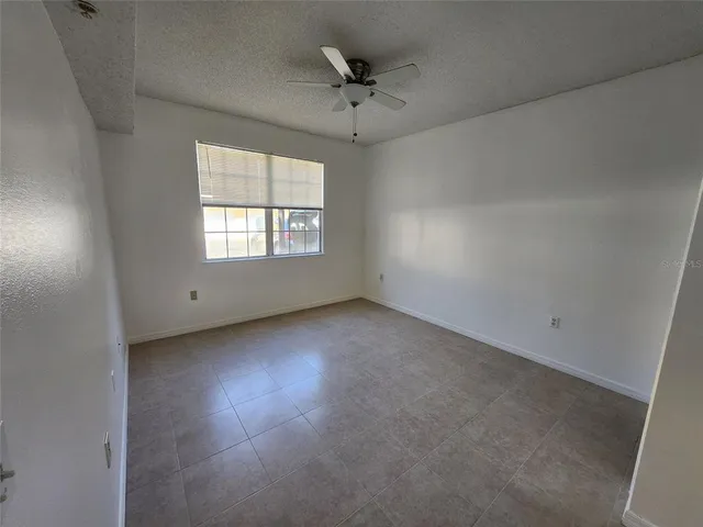 an empty room with a window and a ceiling fan