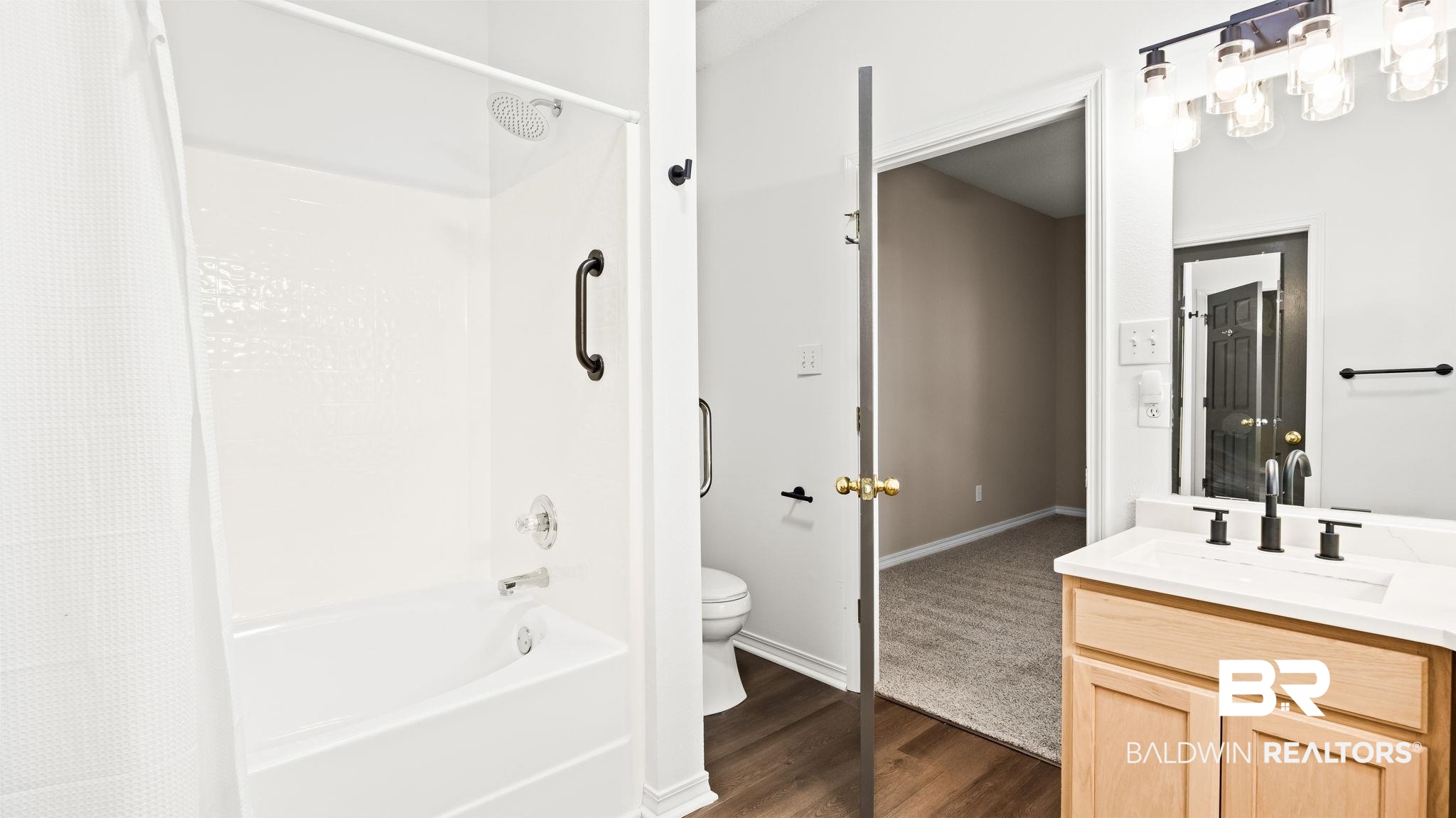 2651 South Juniper Street, Unit 705 Foley, AL 36535 - Photo 18 of 37 Bathroom featuring a white tub and shower combination with a grab bar, wood-finish flooring, a light wood vanity with a white countertop, and a vanity light fixture with clear glass shades