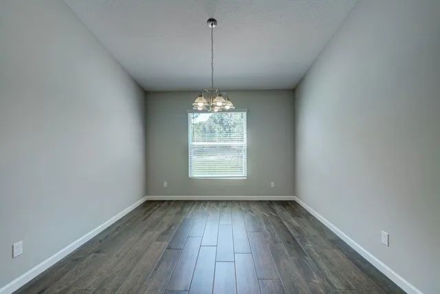 a view of a room with a chandelier fan and kitchen view