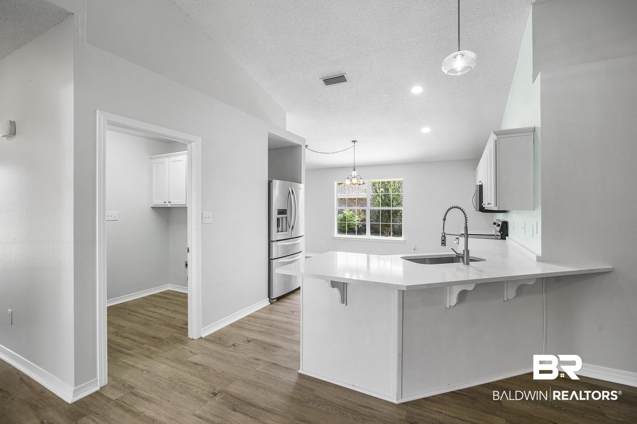9814 Woolrich Avenue Fairhope, AL 36532 - Photo 4 of 29 Kitchen featuring sink, hardwood / wood-style flooring, a breakfast bar area, and stainless steel refrigerator with ice dispenser