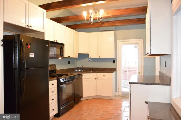 a kitchen with stainless steel appliances granite countertop a refrigerator a sink dishwasher a stove and white countertops with wooden floor