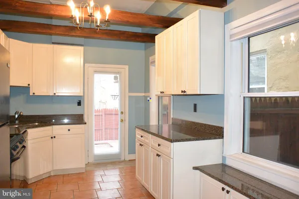 a kitchen with granite countertop a stove a sink and a refrigerator