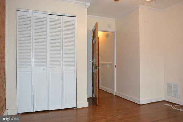 an empty room with wooden floor and closet area