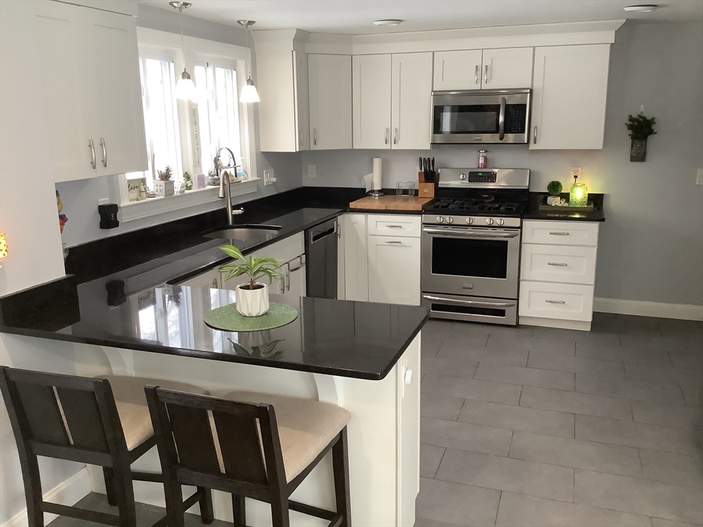 2 Chapel Road Danvers, MA 01923 - Photo 2 of 15 a kitchen with stainless steel appliances granite countertop a stove a sink a microwave a refrigerator and white cabinets