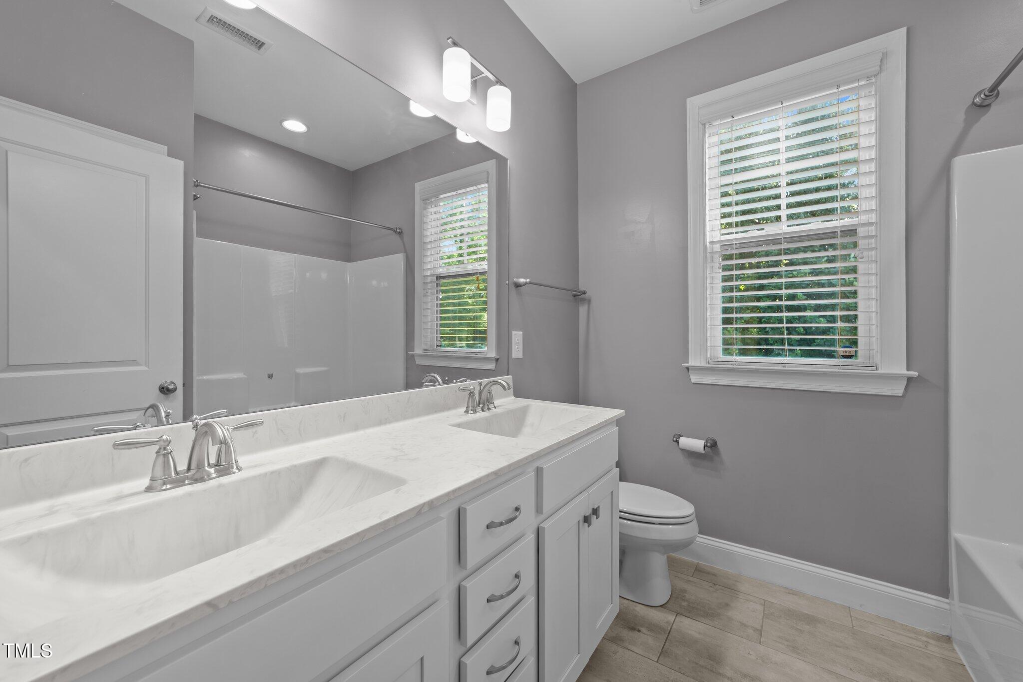 4125 Olde Judd Drive Willow Spring, NC 27592 - Photo 27 of 48 a bathroom with a toilet a sink a mirror a window and vanity