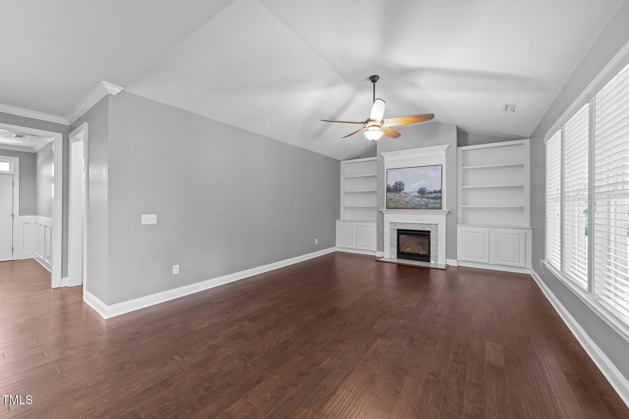 4125 Olde Judd Drive Willow Spring, NC 27592 - Photo 9 of 48 an empty room with wooden floor fireplace and windows