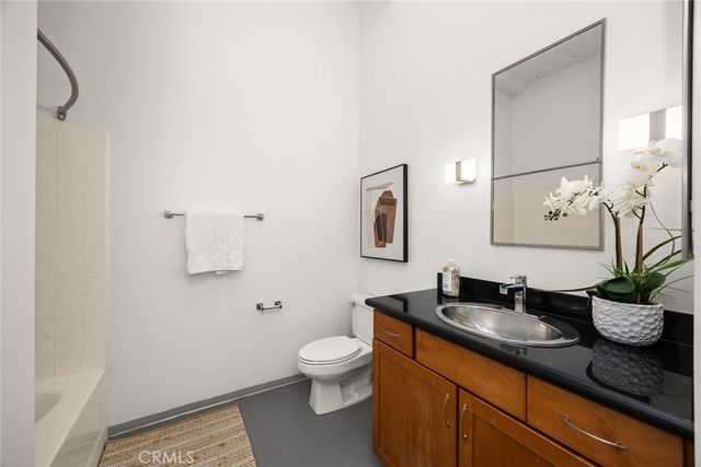 a bathroom with a granite countertop sink a toilet and mirror