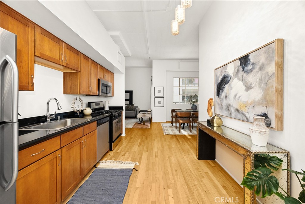420 San Pedro Street, Unit 427 Los Angeles, CA 90013 - Photo 9 of 42 a large kitchen with stainless steel appliances granite countertop a stove a sink dishwasher and cabinets with wooden floor