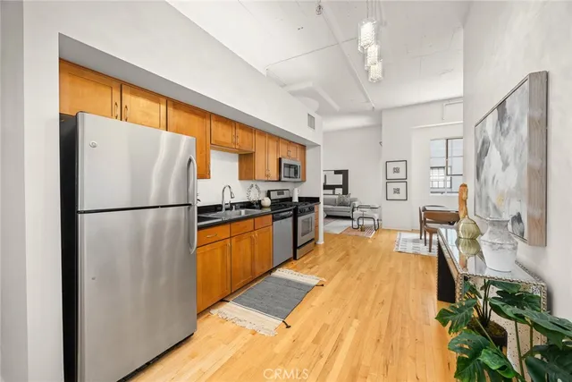 a kitchen with stainless steel appliances granite countertop a refrigerator a stove a sink dishwasher a oven with white cabinets and wooden floor