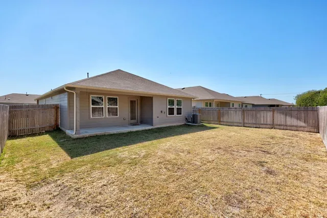 a white house with a small yard and trees in the background