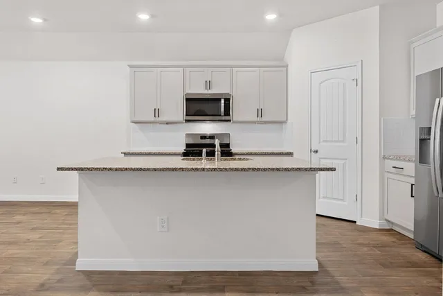 a view of kitchen with stainless steel appliances refrigerator stove microwave and cabinets