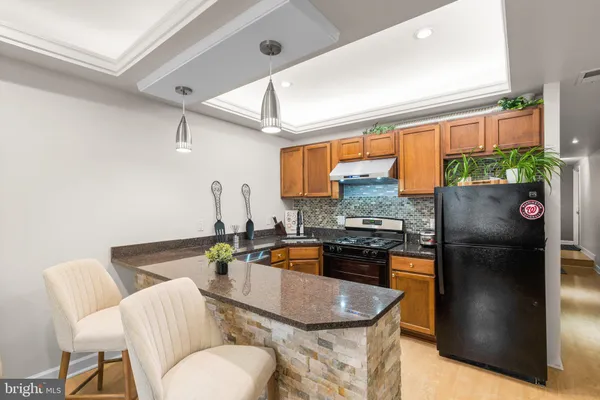a kitchen with stainless steel appliances granite countertop a refrigerator a stove a sink dishwasher and a dining table with chairs