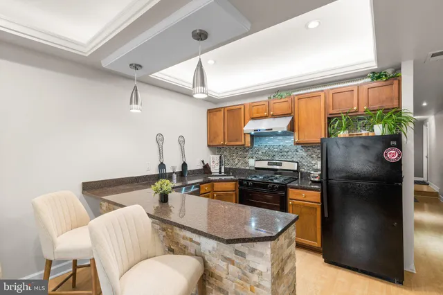 a kitchen with stainless steel appliances granite countertop a refrigerator a stove a sink dishwasher and a dining table with chairs