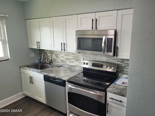 a kitchen with cabinets stainless steel appliances and wooden floor