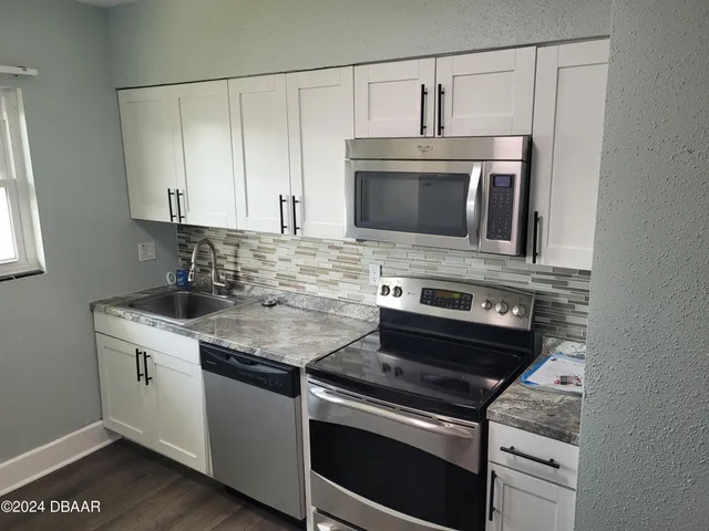 a kitchen with cabinets stainless steel appliances and wooden floor