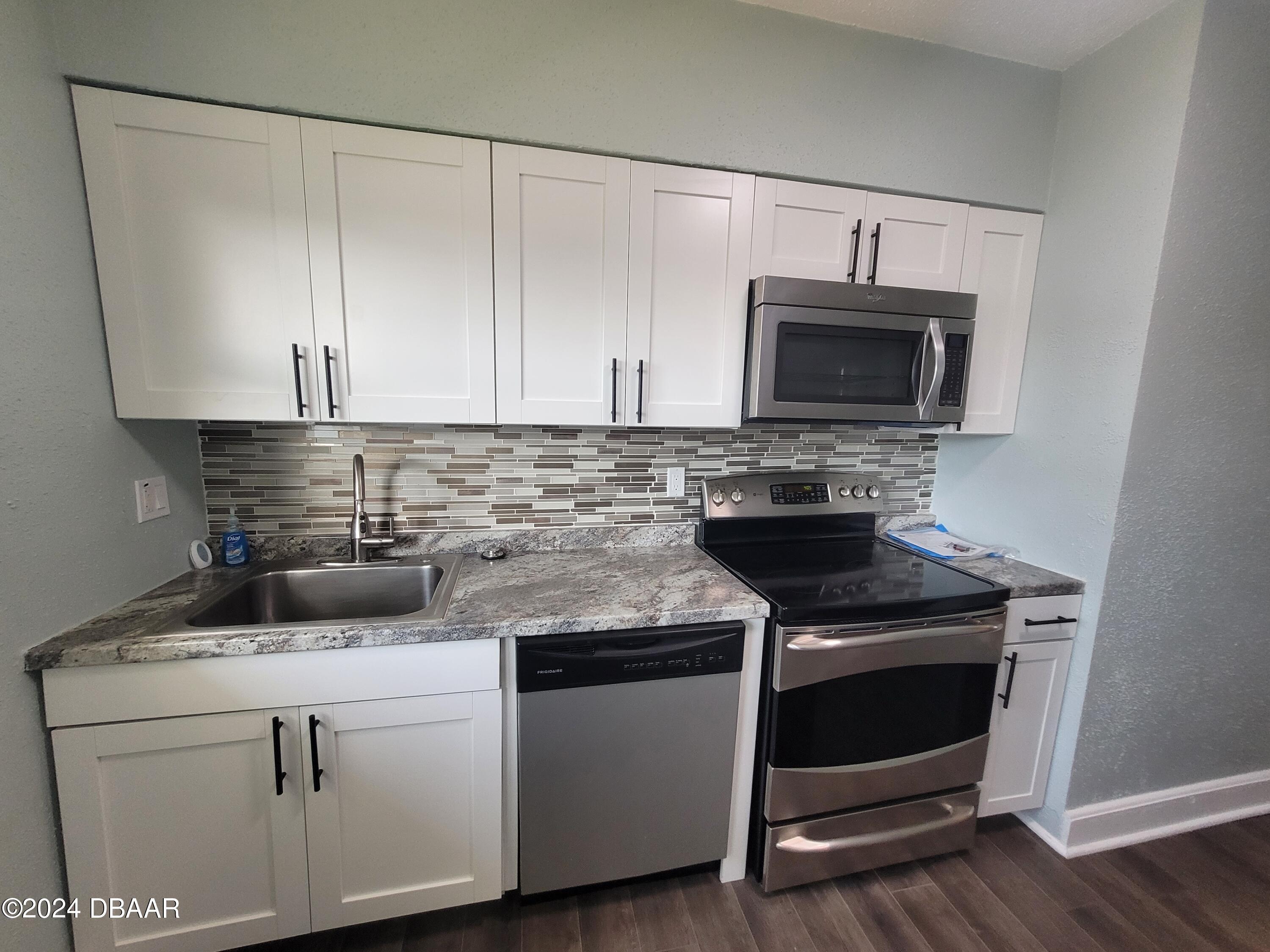500 South Beach Street, Unit J4 Daytona Beach, FL 32114 - Photo 16 of 36 a kitchen with cabinets stainless steel appliances and wooden floor