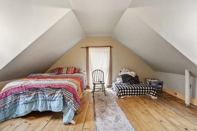 a bedroom with a bed and dresser with wooden floor