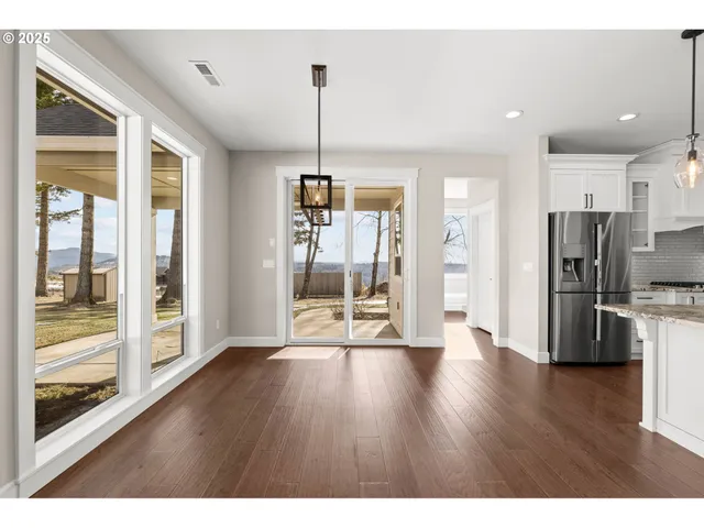 a view of a big room with wooden floor fridge and windows