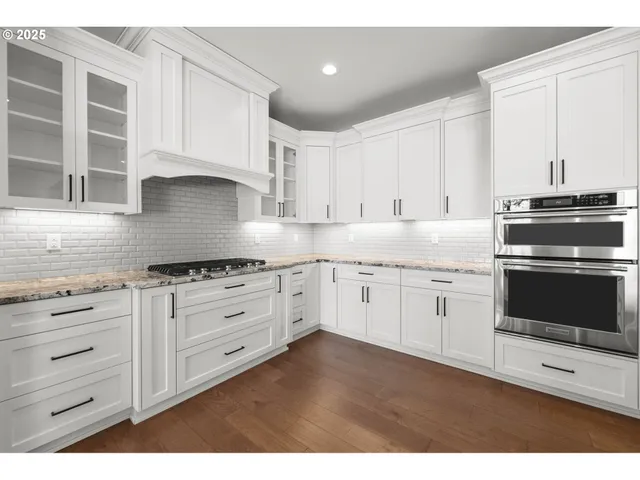 a kitchen with granite countertop white cabinets and stainless steel appliances