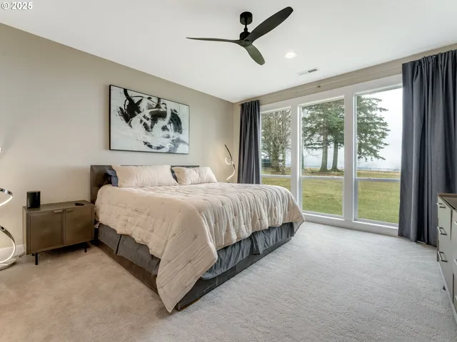 a spacious bedroom with a bed painting and a large window