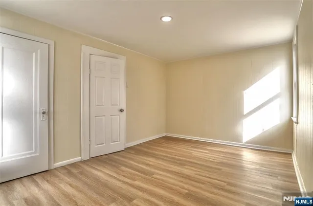 an empty room with wooden floor and windows with curtains