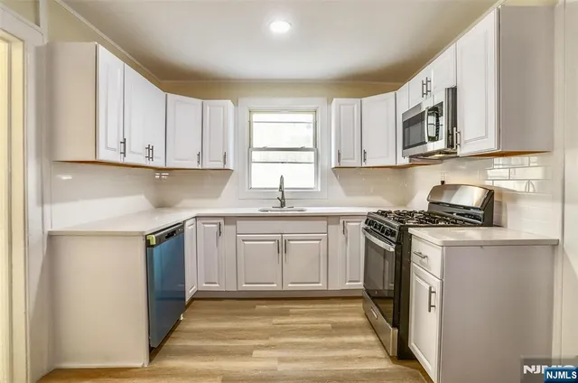 a kitchen with stainless steel appliances granite countertop a stove a sink and a microwave