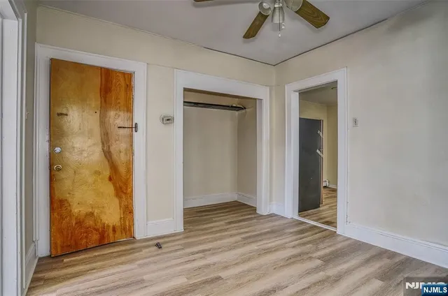an empty room with wooden floor closet and windows