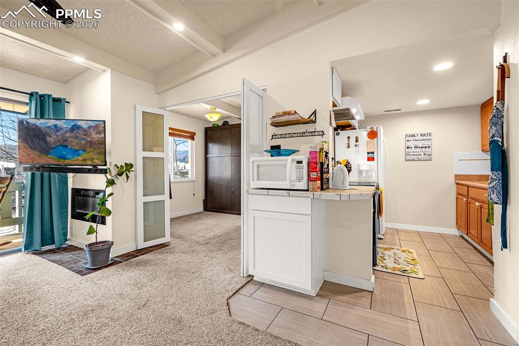 1018 Fontmore Road, Unit C Colorado Springs, CO 80904 - Photo 14 of 29 Kitchen with tile countertops, white microwave, a textured ceiling, beamed ceiling, and light colored carpet