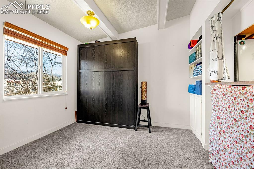 1018 Fontmore Road, Unit C Colorado Springs, CO 80904 - Photo 2 of 29 Bedroom with light carpet, a textured ceiling, and beamed ceiling