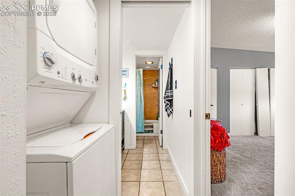 1018 Fontmore Road, Unit C Colorado Springs, CO 80904 - Photo 6 of 29 Laundry area featuring light carpet, stacked washer / drying machine, light tile patterned floors, and a textured ceiling