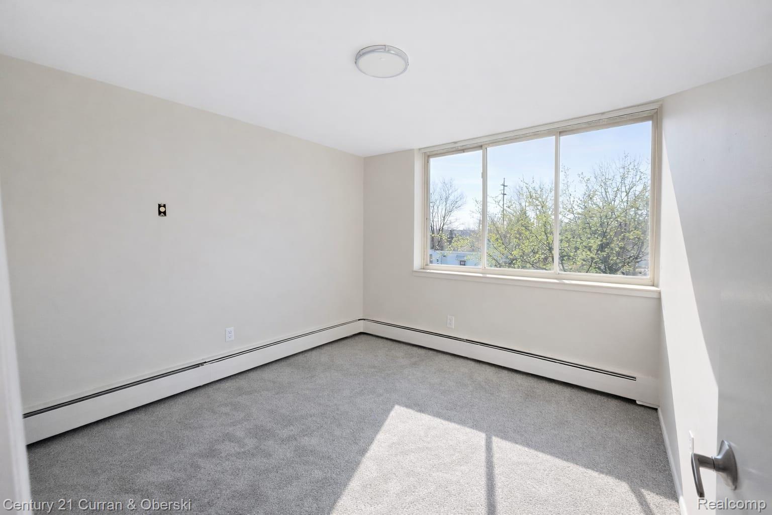 6015 Southfield Road, Unit 6 Detroit, MI 48228 - Photo 7 of 10 Spare room with a baseboard radiator and light carpet