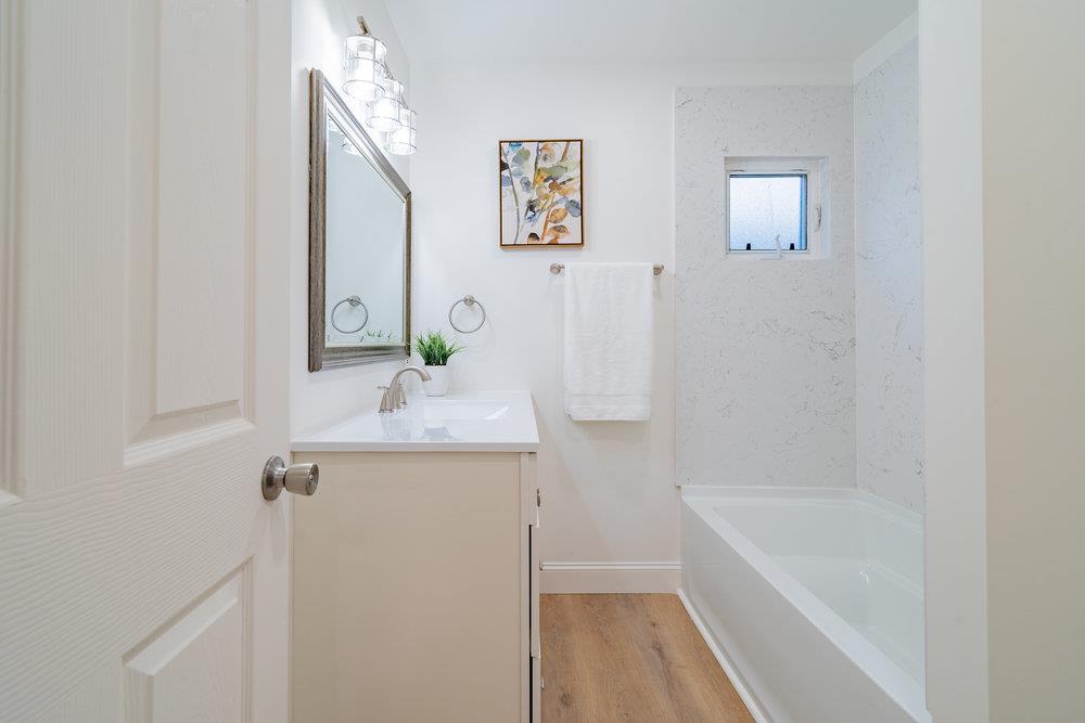 741 West 6th Street Gilroy, CA 95020 - Photo 24 of 29 a bathroom with a granite countertop sink a mirror and a bathtub