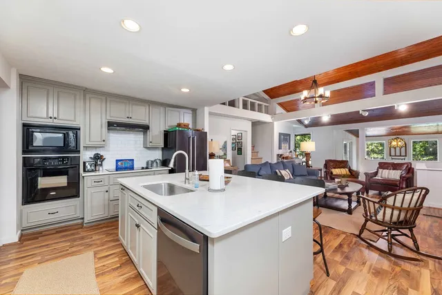 a kitchen with stainless steel appliances granite countertop a table chairs sink and cabinets