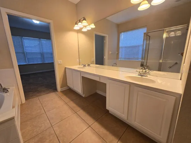 a spacious bathroom with a double vanity sink a mirror and a bathtub