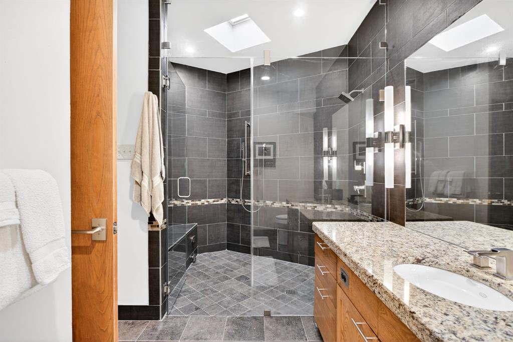 1080 North Greenbrier Road Nocona, TX 76255 - Photo 19 of 40 Spacious bathroom featuring a glass-enclosed shower with a built-in bench, a rain showerhead, and a skylight