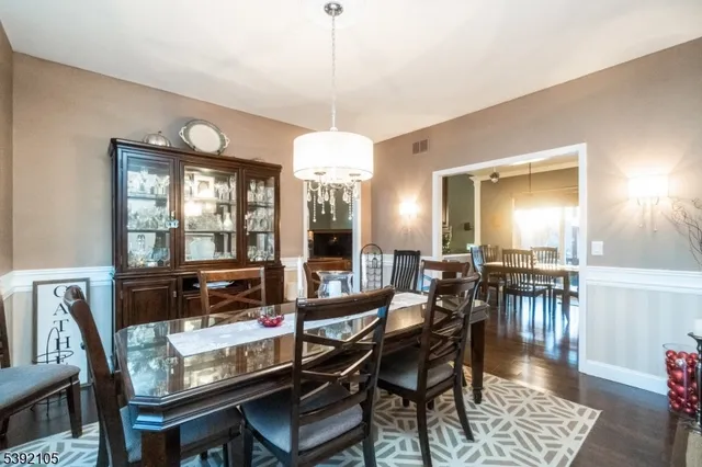 a dining room with wooden floor a chandelier a wooden table and chairs