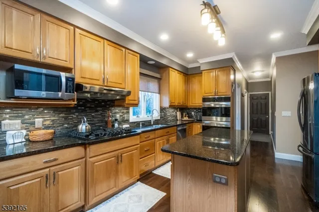 a kitchen with stainless steel appliances granite countertop a sink a stove cabinets counter space and a window