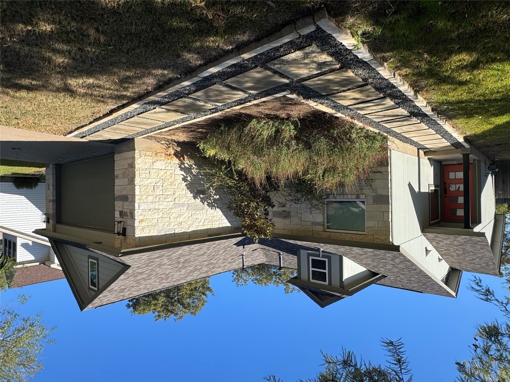 a view of a house with a small yard plants and large tree