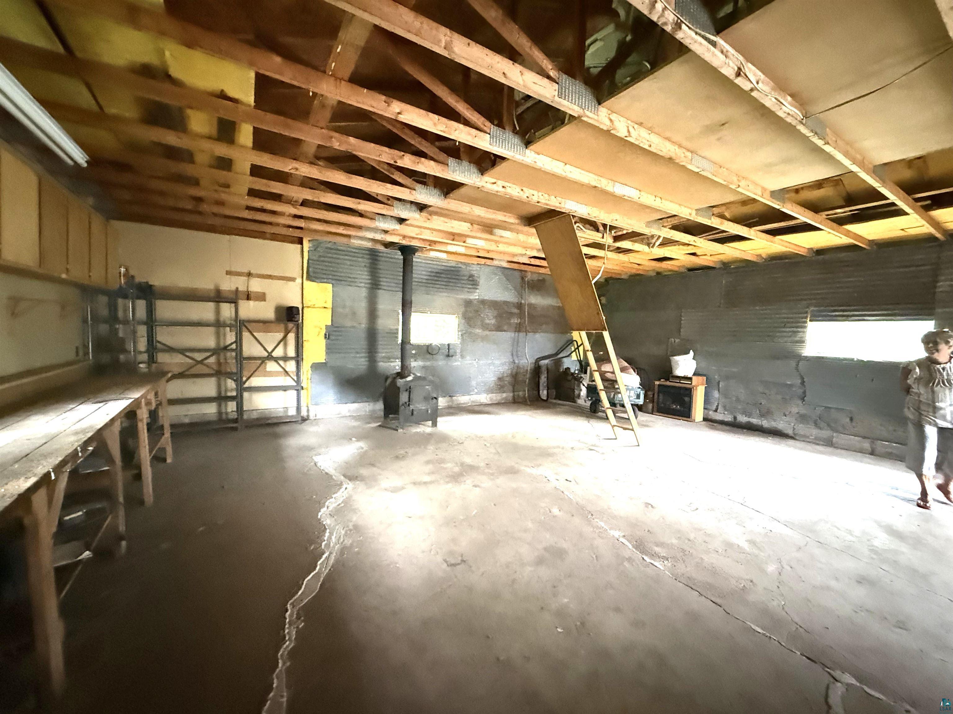 3541 Bent Trout Lake Road Barnum, MN 55707 - Photo 33 of 41 Utility space featuring exposed ceiling joists, a wood-burning stove, concrete flooring, and multiple windows