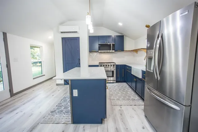 a kitchen with stainless steel appliances granite countertop a refrigerator a stove and a sink with wooden floor