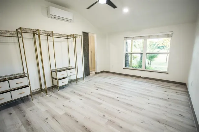 an empty room with wooden floor fan and windows